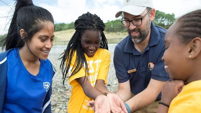 youth campers with adults wearing yellow and blue shirts outdoors