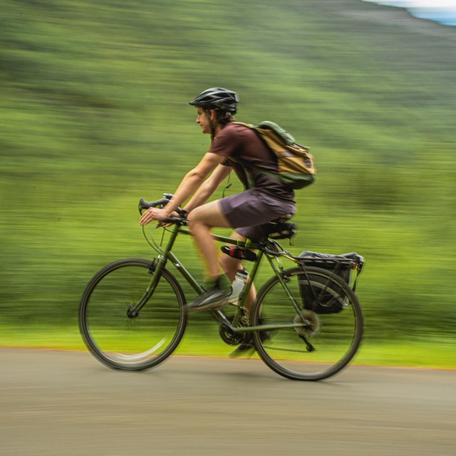 a man wearing a helmet bicycles on a path