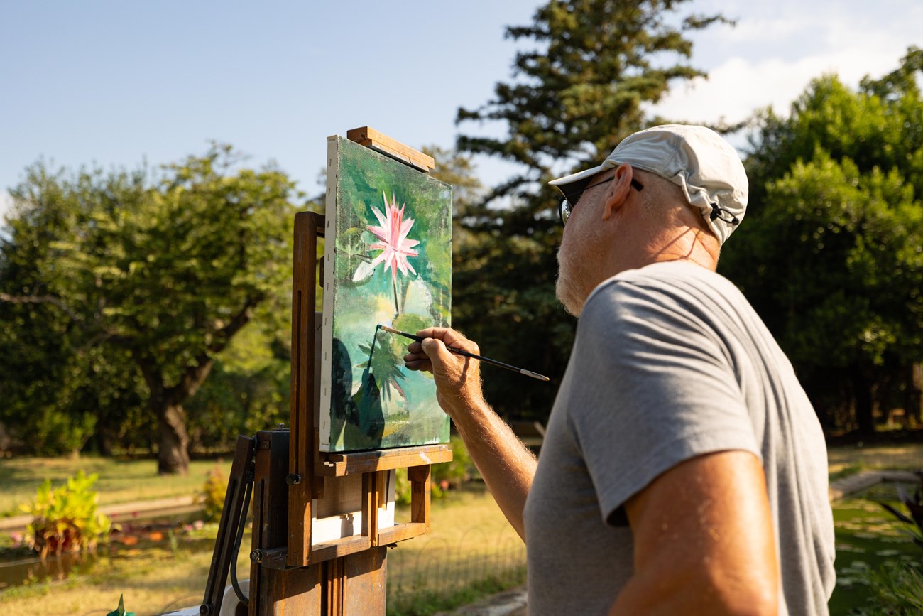 An artist paints a lotus flower on a large canvas