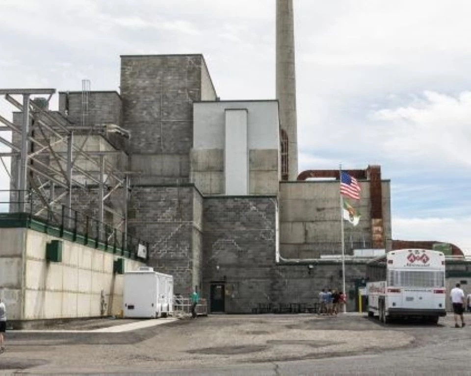 Black and white photo of brick factory buildings with a white chimney