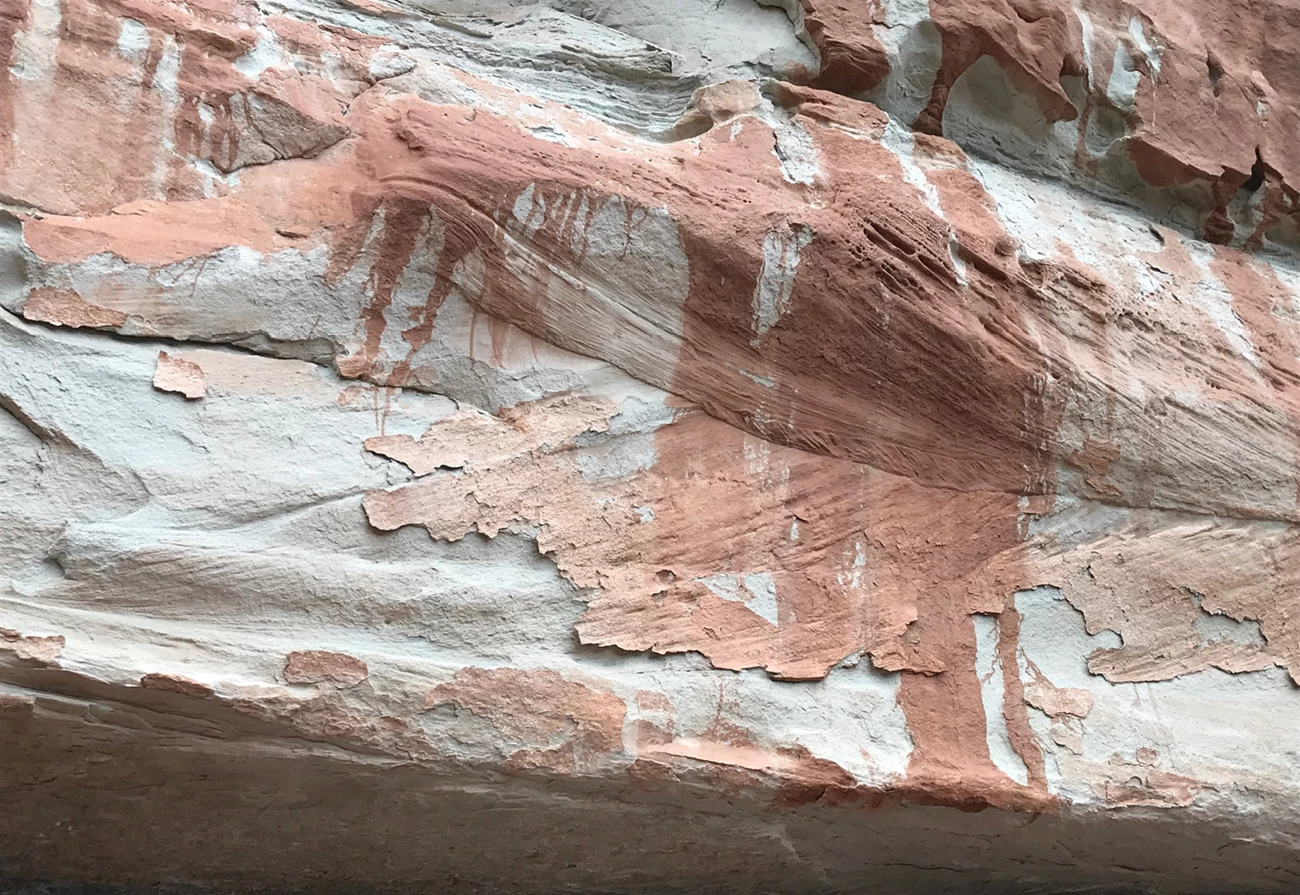 Photo of rock overhang with red streaks and text "cast hardening".