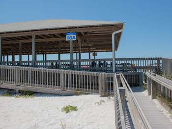 A wooden ramp leading up into a wooden open air structure. A white and blue metal sign with the text, 