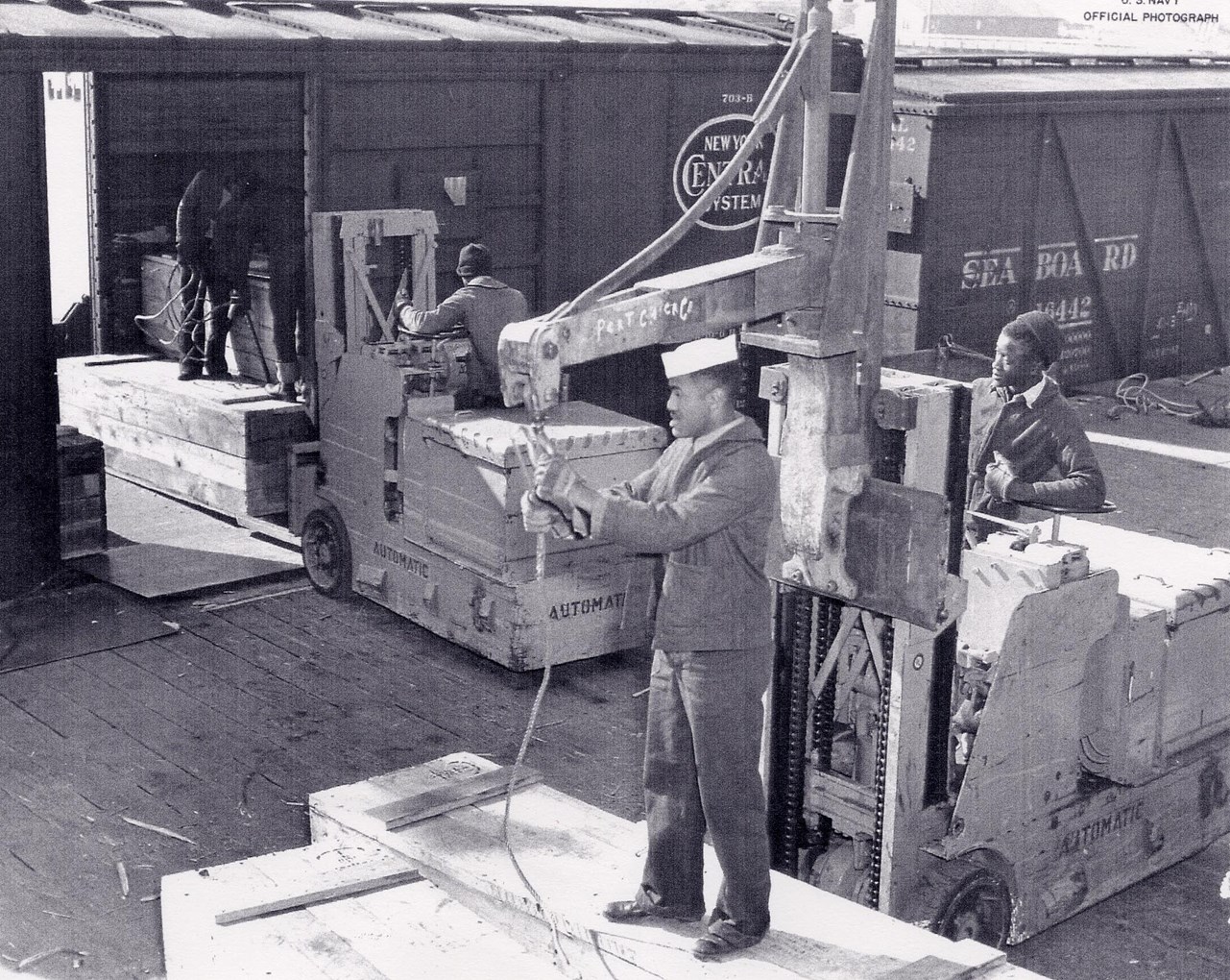 Historic Black and white photo of African American sailors loading munitions onto a rail car.