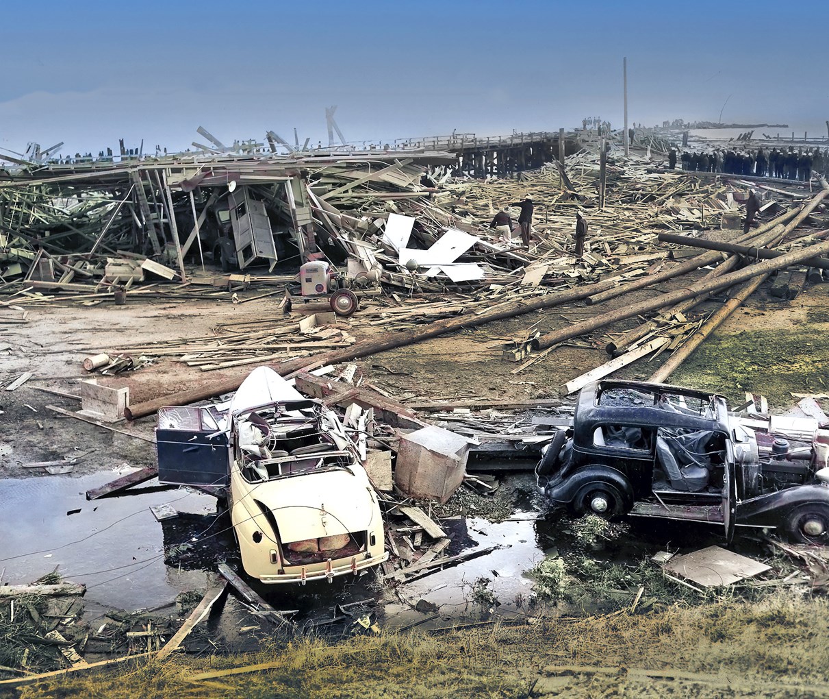 Historic Black and white photo of the disaster aftermath. Two cars and a lot of debris from buildings.