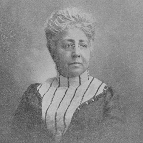 A portrait of a woman wearing a dress with stripes with glasses and hair in an updo