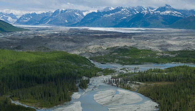 landscape with distant mountains and a river running through spruce forest