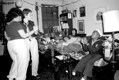 People dancing and lounging on a couch in a living room for a birthday party