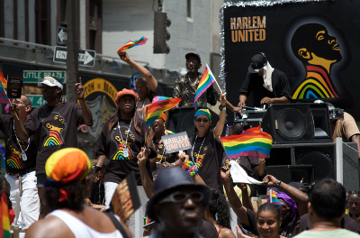 A crowd of people with rainbow flags and a sign that says 