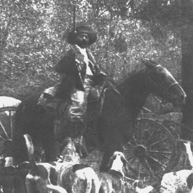 black and white image of man on horse, with gun, and hounds at his feet. black and white image of man on horse, with gun, and hounds at his feet.