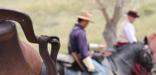 A rusted bell and costumed cavalry riders in the background