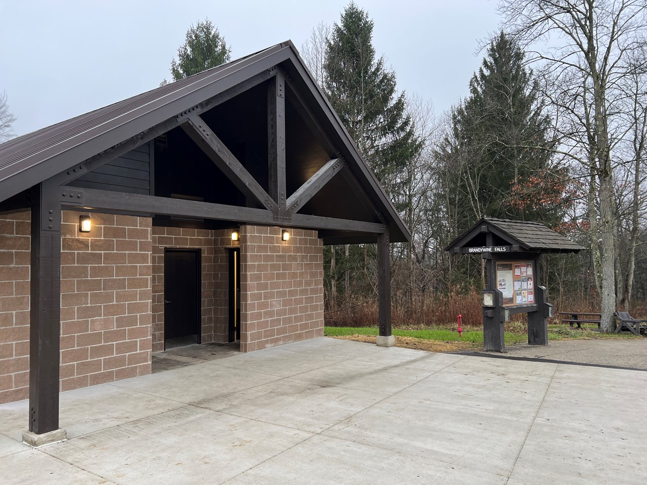 A brick restroom facility with a paved path and a sign in front.