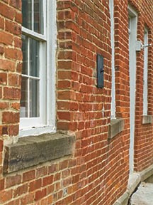 Exterior of a red brick building with stone window sills and white wooden windows.