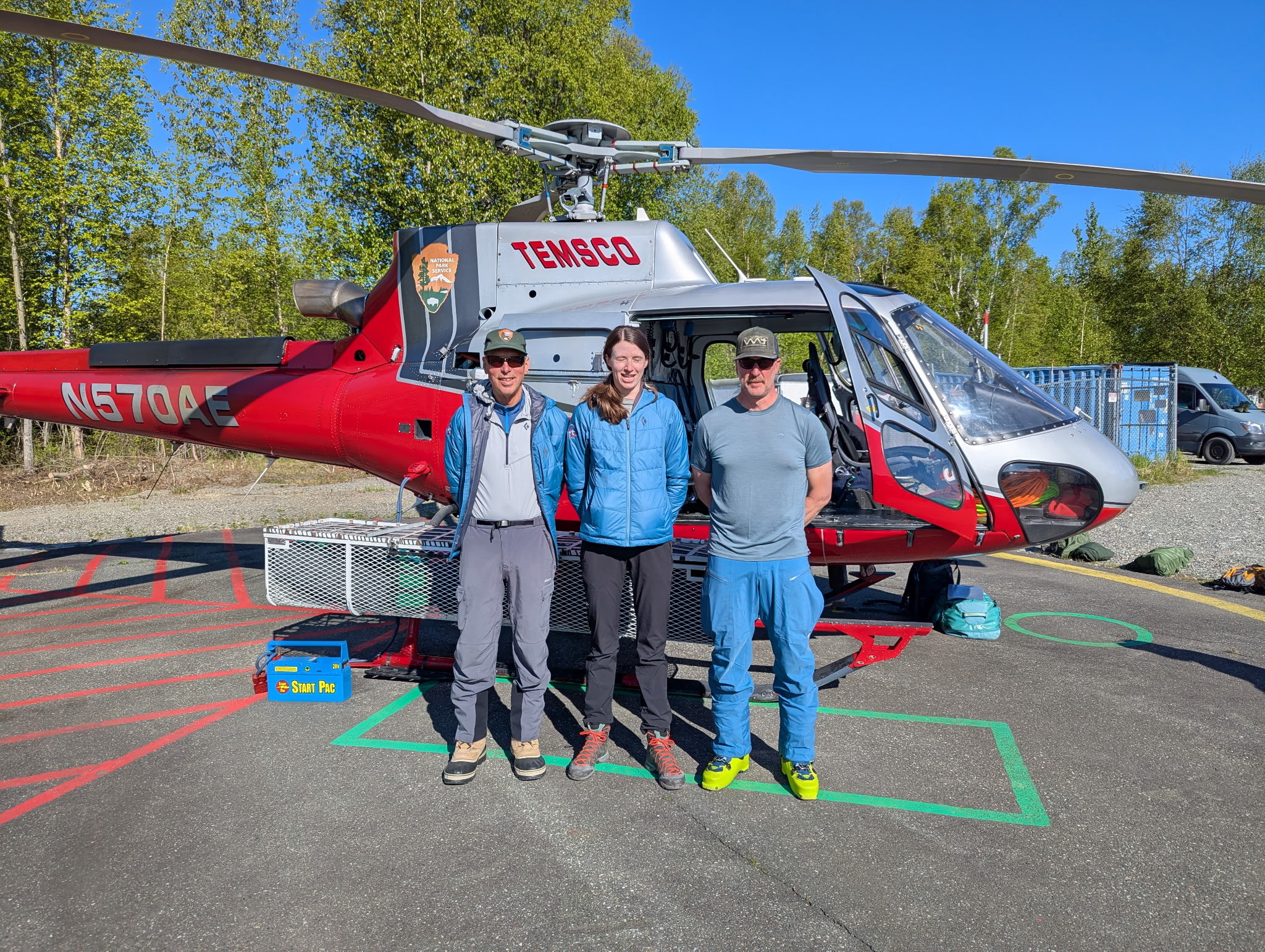 BC Patrol #2 Mock Team Photo 3 rangers stand in front of a red helicopter