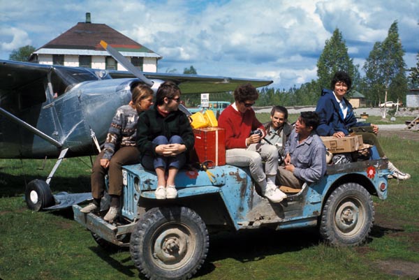 A jeep full of women pose in front of a small aircraft