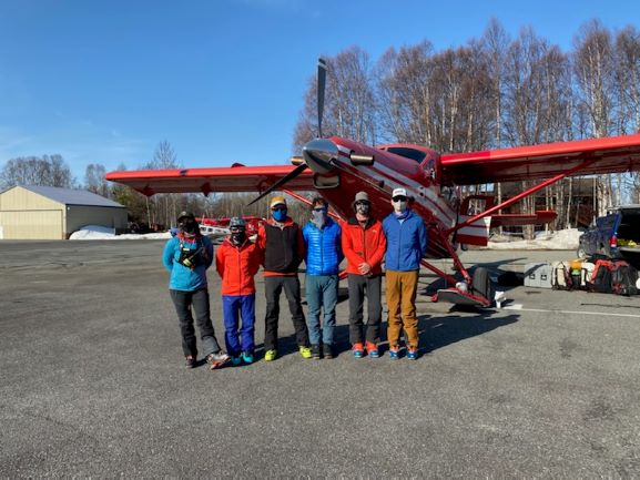 Six masked climbers outside a small aircraft