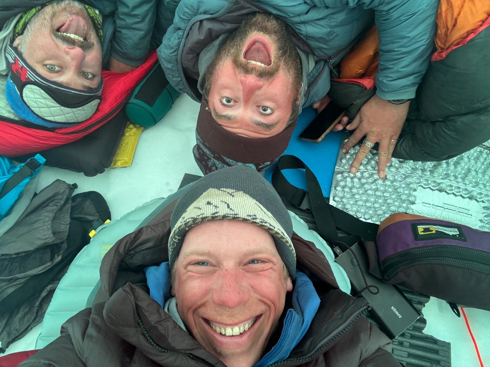Patrol 2 Team Photo B 3 rangers in full winter gear shown from above laying on the ground with joyful expressions