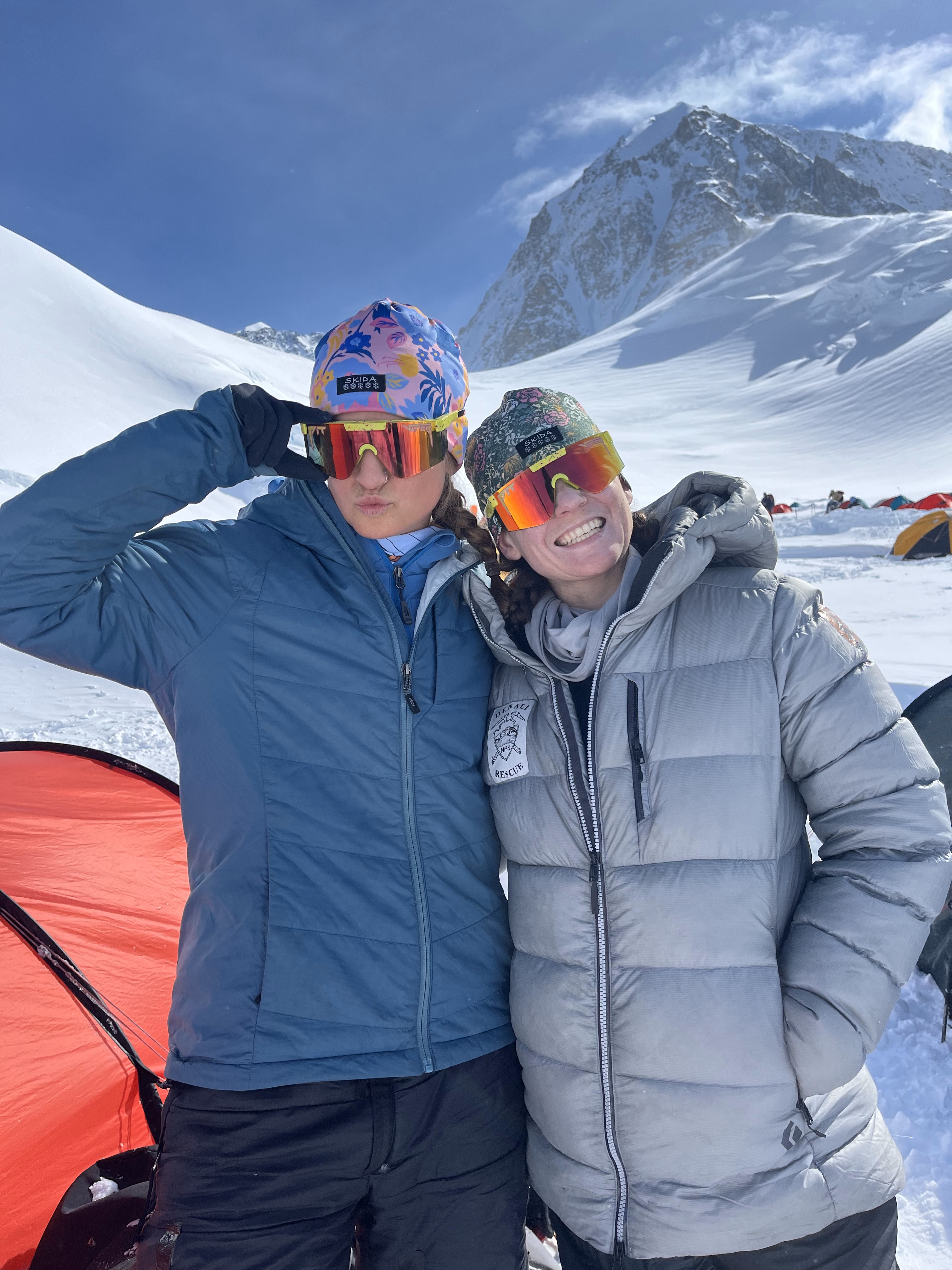 Patrol 3 Team Photo B 2 rangers wearing mirrored ski glasses and down coats pose in front of red tent and a snow covered mountain
