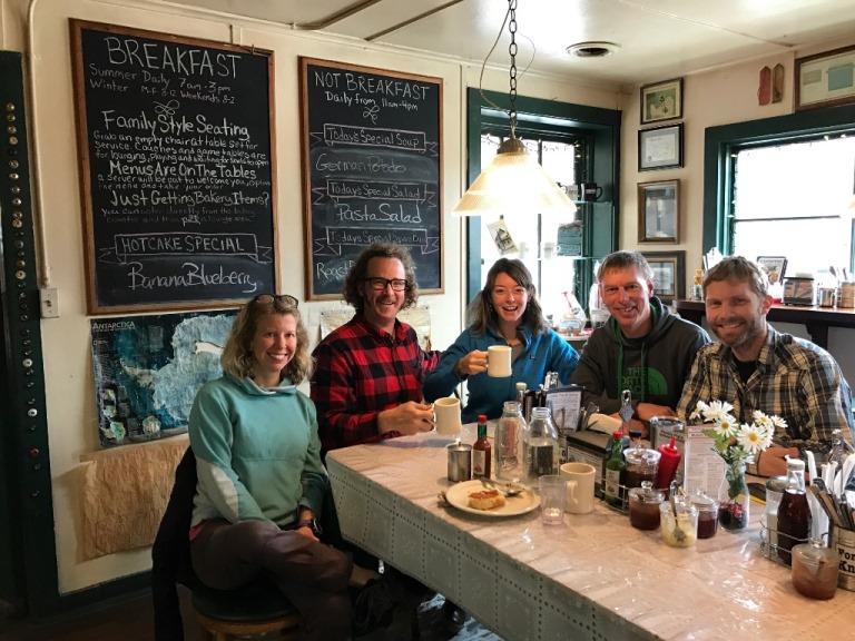 Five mountaineers sit around a breakfast table