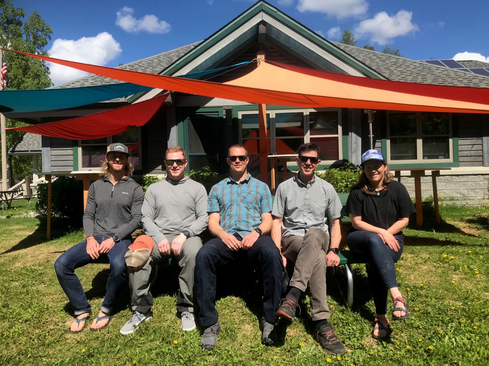 Five patrollers sit at a picnic table under colorful tarps