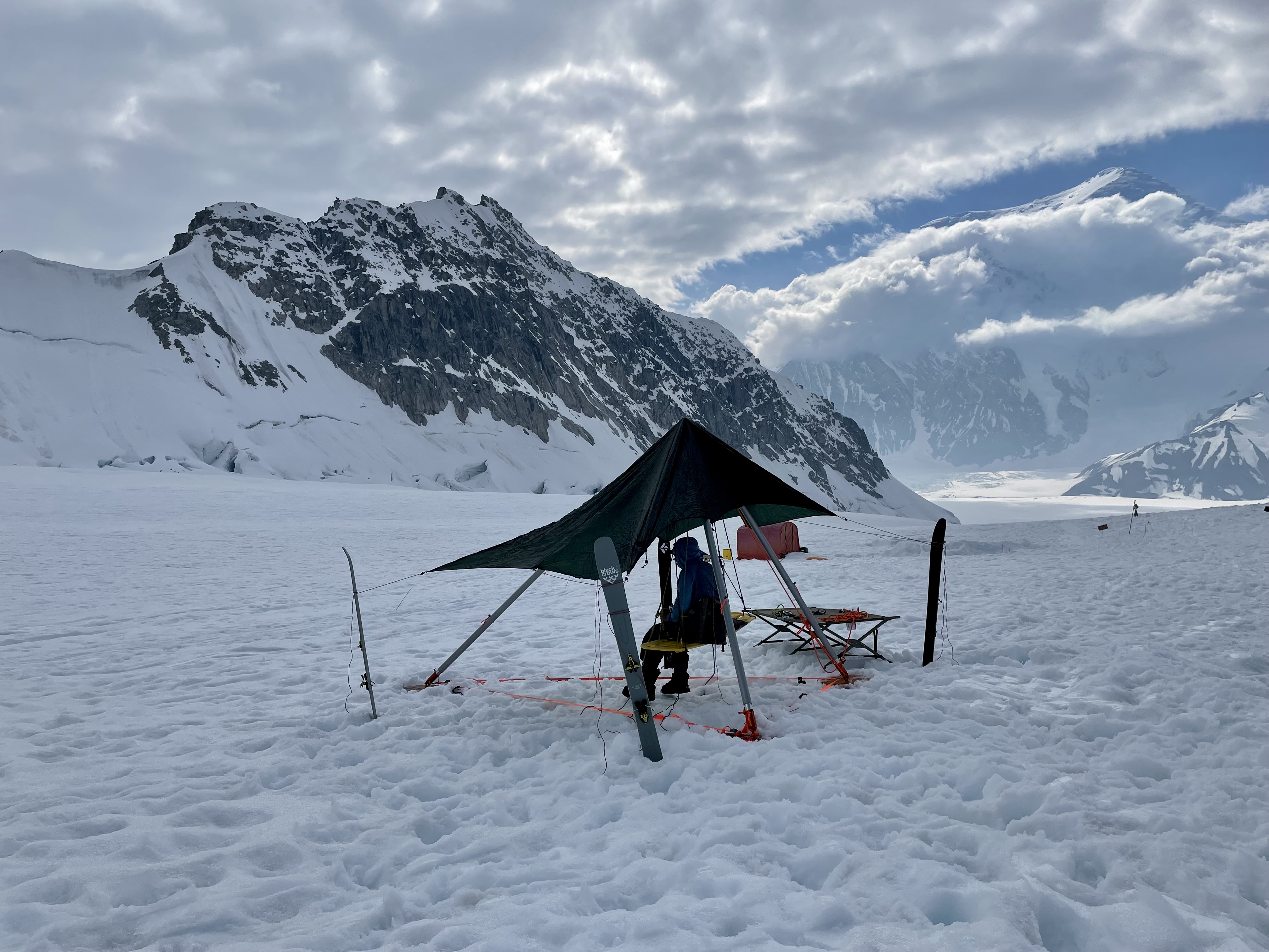 A climber sits on an improvised swing hanging from a large tripod.