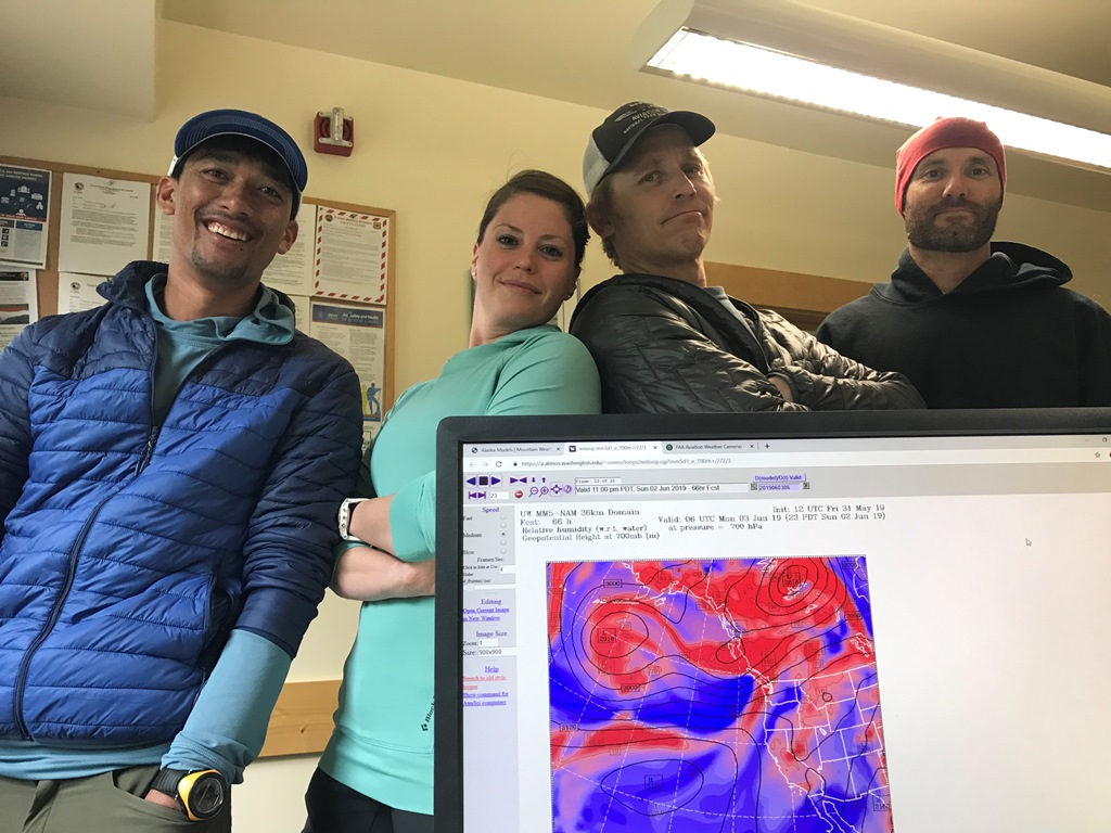 Four patrol members surround a computer screen showing weather mapping