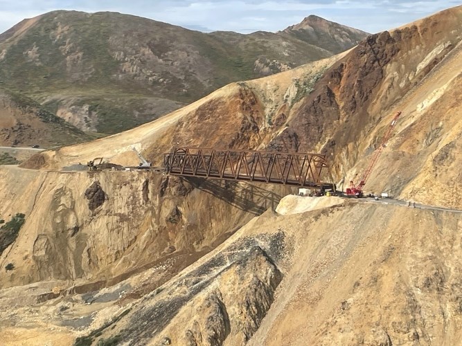 An aerial image taken from the east side of the Pretty Rocks Bridge. The bridge spans the entire landslide and there is construction equipment parked on both sides.