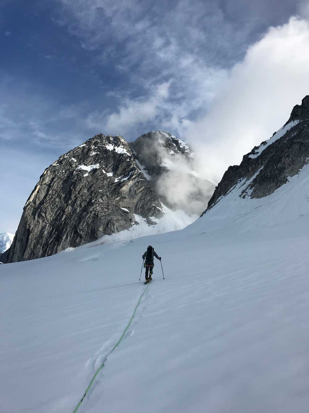 man climbing high on a snowy mountain near a craggy peak