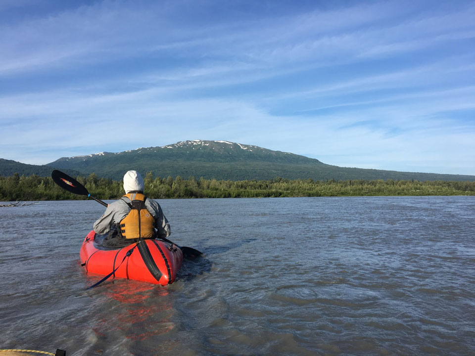 a man floating down a river in a pack raft