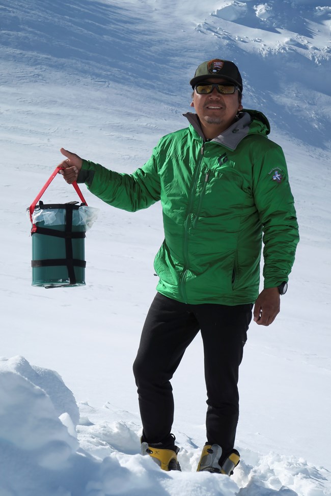 A mountaineer holds up a Clean Mountain Can