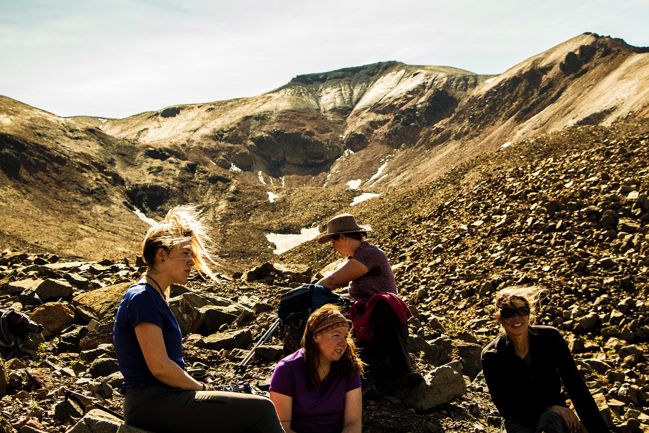 Four people atop a rock-strewn mountain on a sunny day