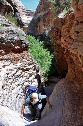 A hiker climbs some of the rocky slopes in Lower Sand Canyon.