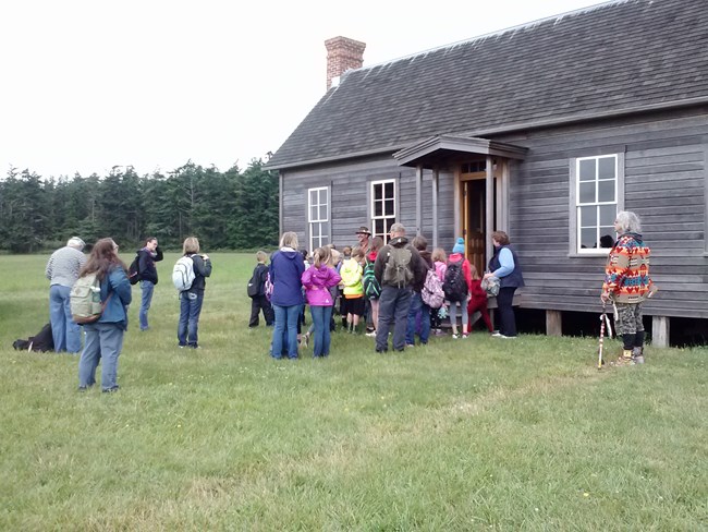 Group of school children visiting historic farmhouse.