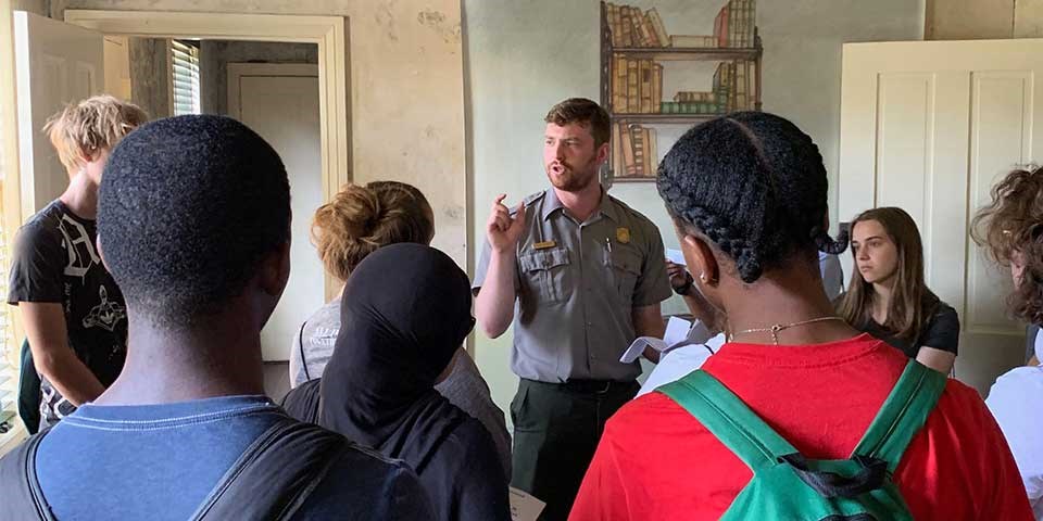 Park ranger speaks to a group of teens in the Poe House parlor.