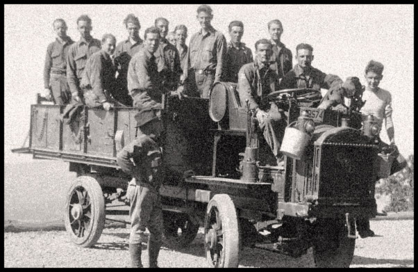 A dozen boys in the back of an open truck pose for a photo.