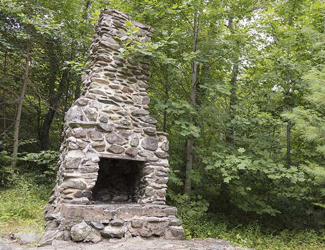 A modern day view of the large outdoor fireplace and chimney.