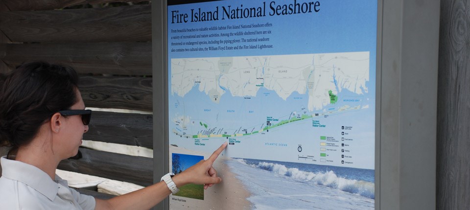 A woman looks at a park map on a wayside.