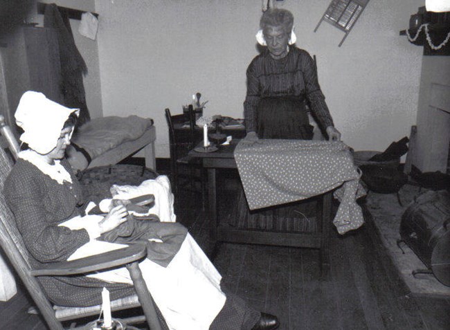 Two laundresses mend clothing in laundress quarters