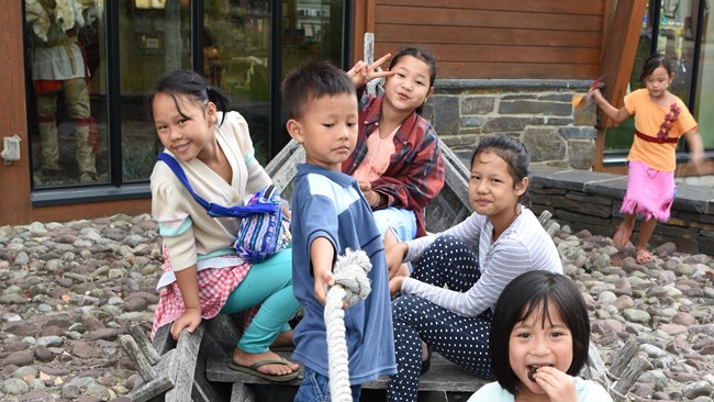 Several small children sit in a boat smiling at the camera.