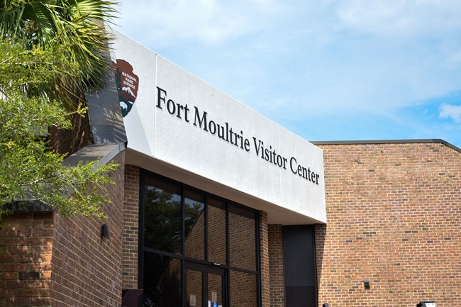 The visitor center on a bright clear day. A palm tree is on the left.