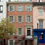 the red brick petersen house with light blue shutters and a lamppost out front