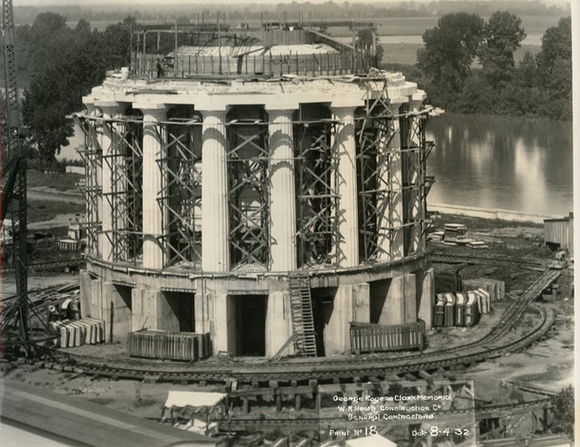 Construction on the memorial continues, doric columns are complete and the roof is being worked on. Parapet walls are not yet in place. Many wood forms and scaffolds still stand in place to assist workers in ascending and descending the memorial.