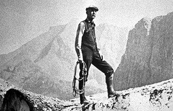 historic image of thin man with mustache holding coiled rope standing on ice