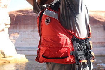 Lifejacket being worn by man boating through canyon