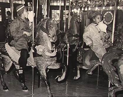 Black children on carousel eating cotton candy