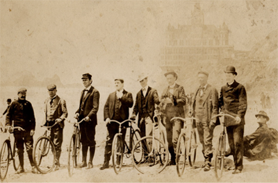 Historic photo showing group of men standing next to their bicycles.