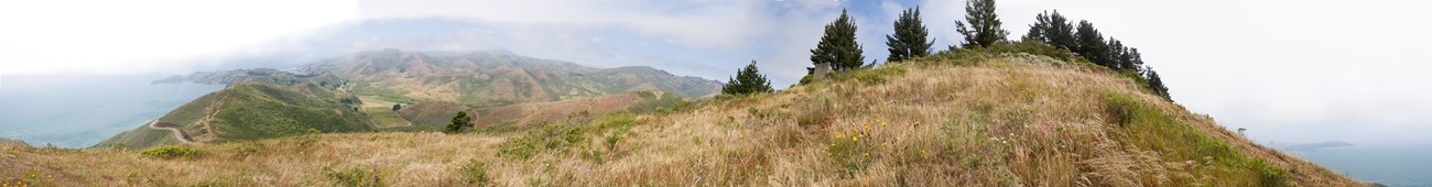 The view of the rolling green Marin Headlands and the long arm of Point Bonita on a slightly cloudy day.