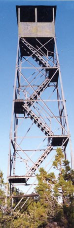 Looking up a a grey metal fire tower around four stories tall.