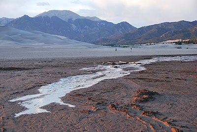 Medano Creek at trickle flow, dunes, and snow-free mountain