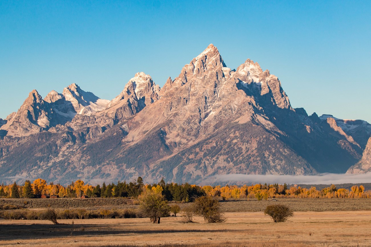 Craggy, snow-capped peaks rise abruptly out of flat plains.