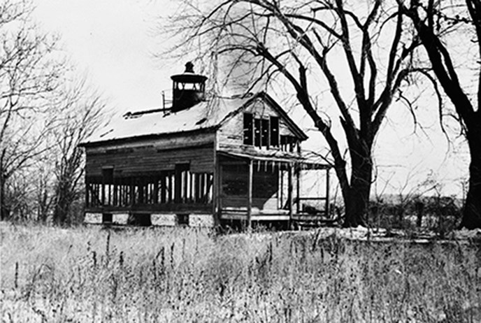 Lighthouse with broken windows and sagging porch.